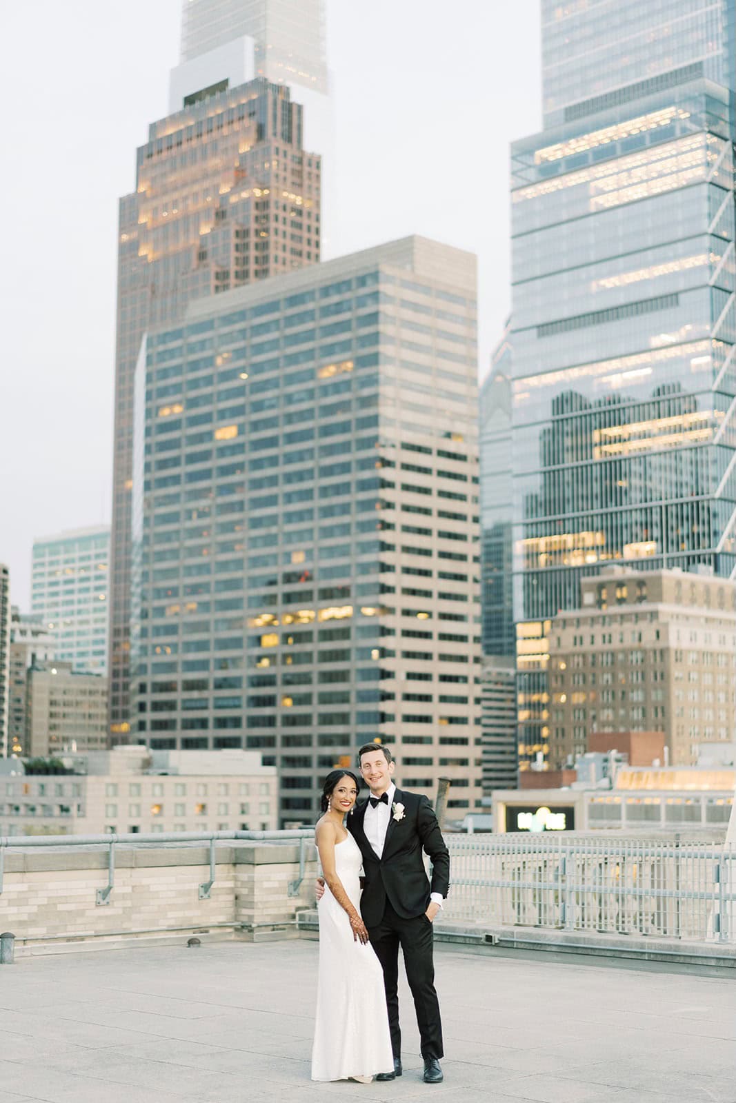 Bride and groom on a rooftop in downtown Philadelphia with skyline backdrop