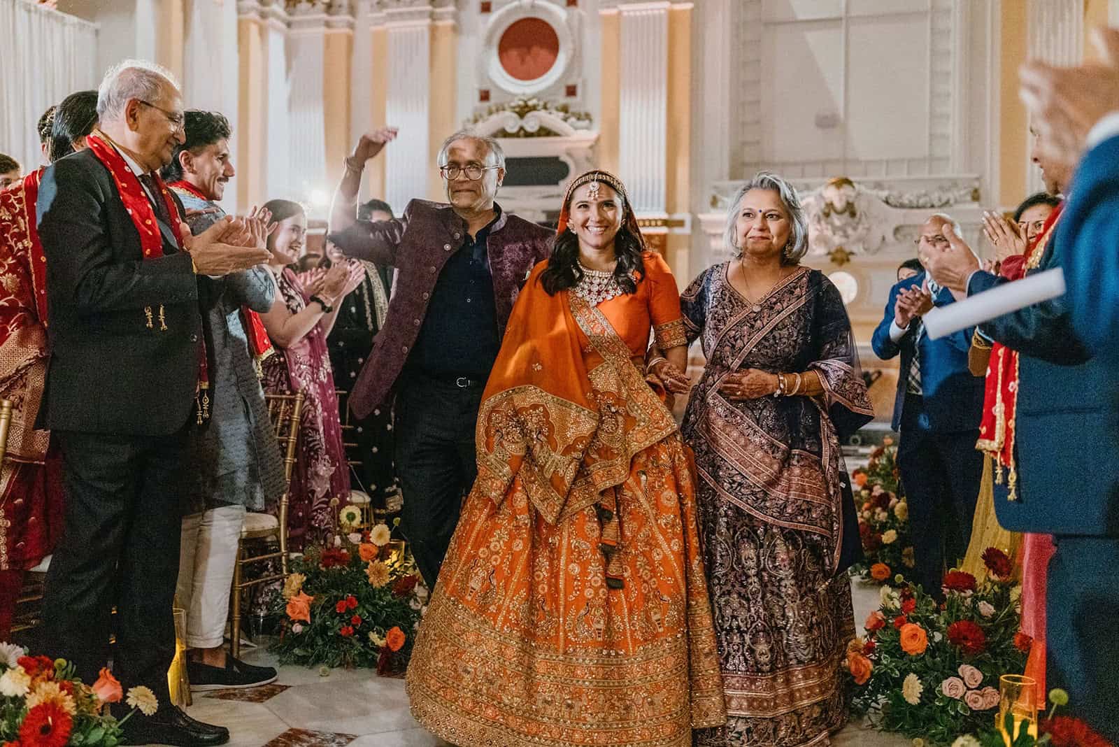 Bride with parents walking down the aisle at the South Asian wedding ceremony